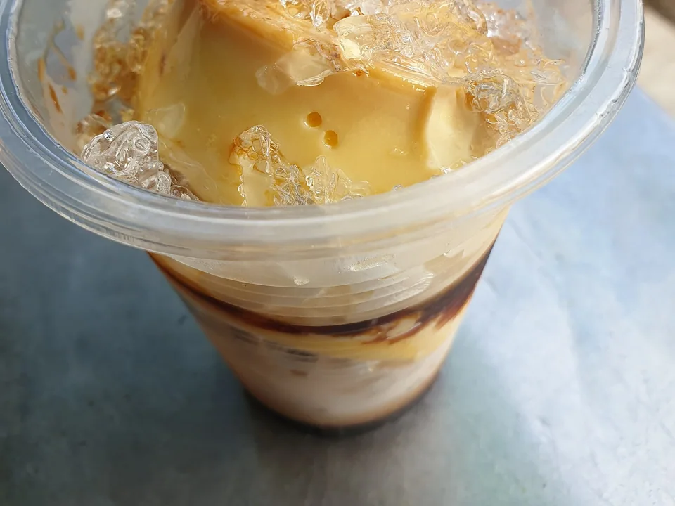 Vietnamese caramel custard in a cup with dark coffee and crushed ice