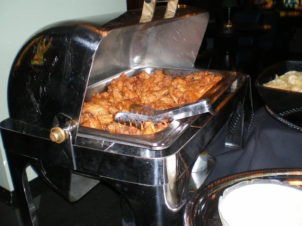 Buffalo wings glazed with hot sauce beside celery and blue-cheese dip