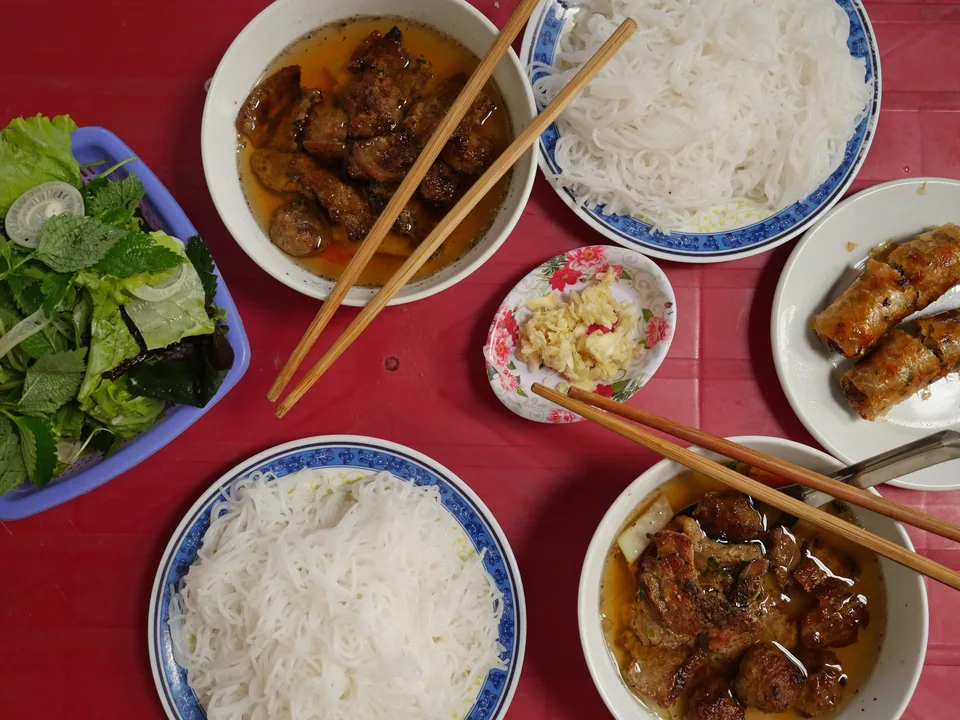 Grilled pork patties in light dipping sauce with pickles, rice noodles and herbs
