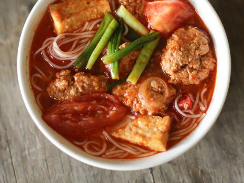 Tomato-red bun rieu with crab dumplings, tofu, pork ribs, rice noodles and herbs