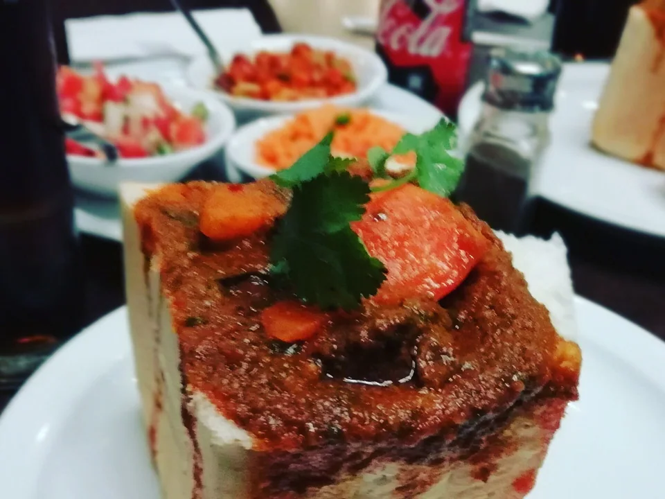 Durban mutton bunny chow curry in a hollow white bread quarter with potato and tomato-onion salad