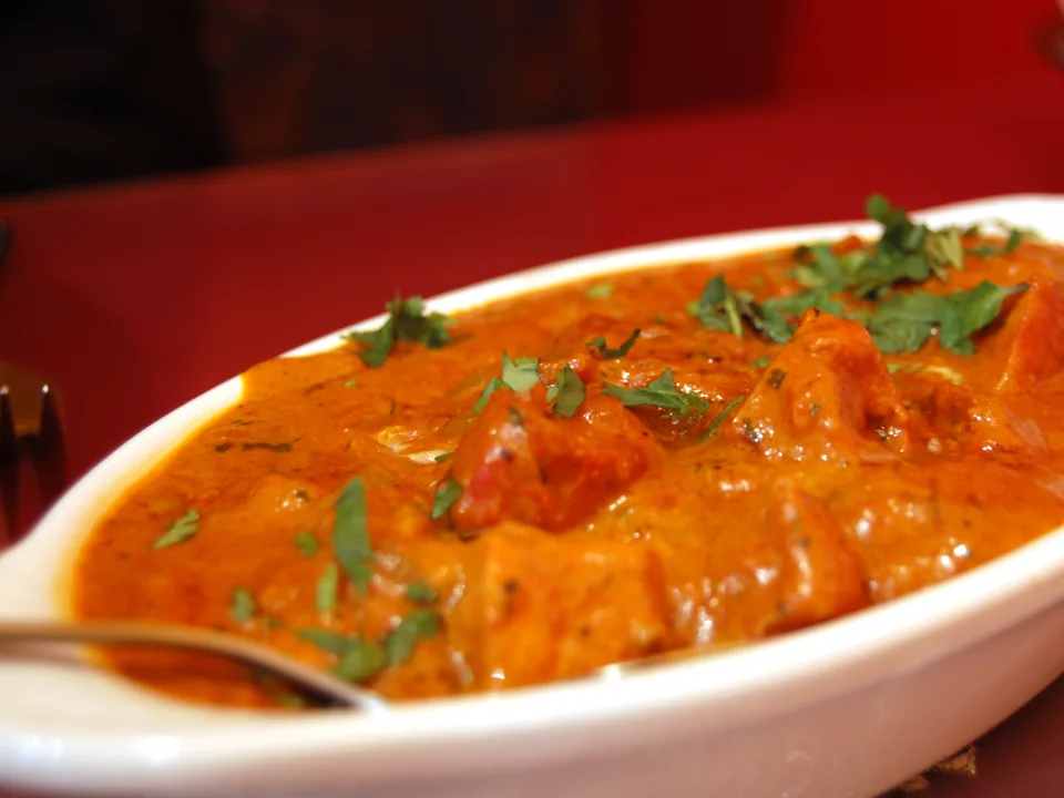 Butter chicken in silky orange-red tomato cream sauce with charred chicken pieces and fenugreek