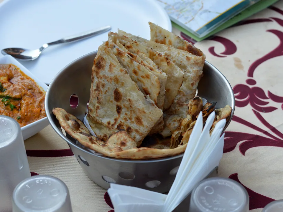 Soft butter naan with puffed centre, dark tandoor-style blisters, and melted butter sheen