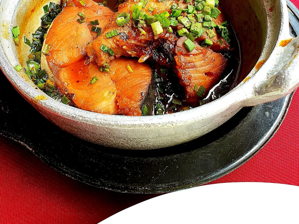 Caramel-braised fish steaks in glossy brown sauce with scallions and pepper