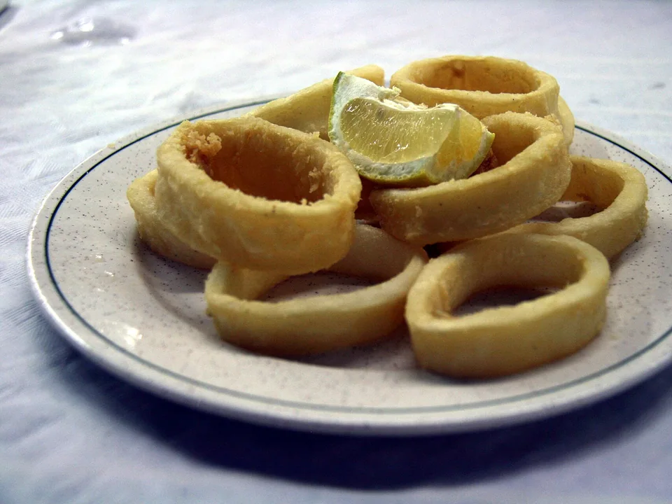 Crisp golden Spanish battered squid rings with lemon wedges
