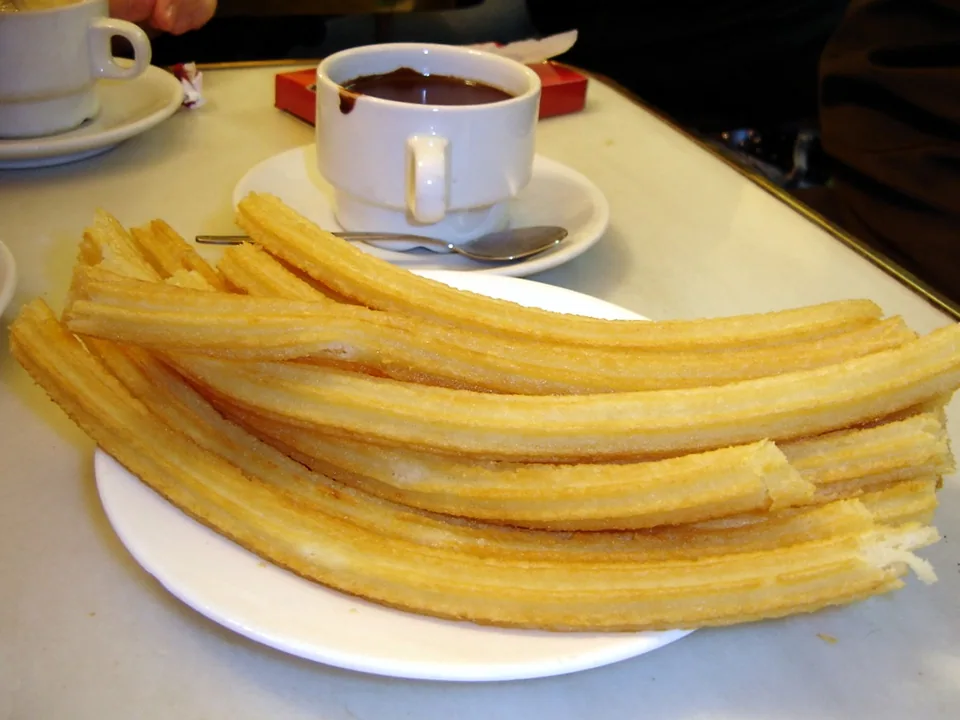 Golden Spanish churros with thick dark hot chocolate for dipping