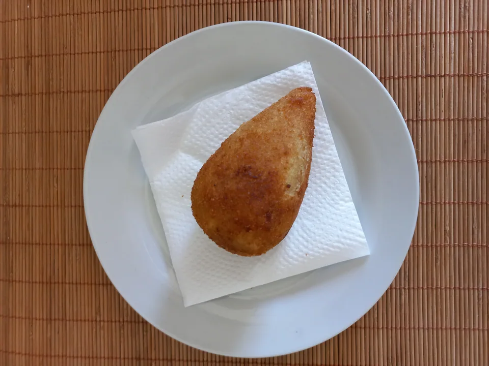 Golden teardrop coxinha filled with seasoned shredded chicken