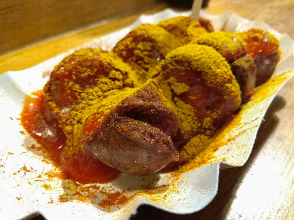 German currywurst slices under thick tomato curry sauce with curry powder