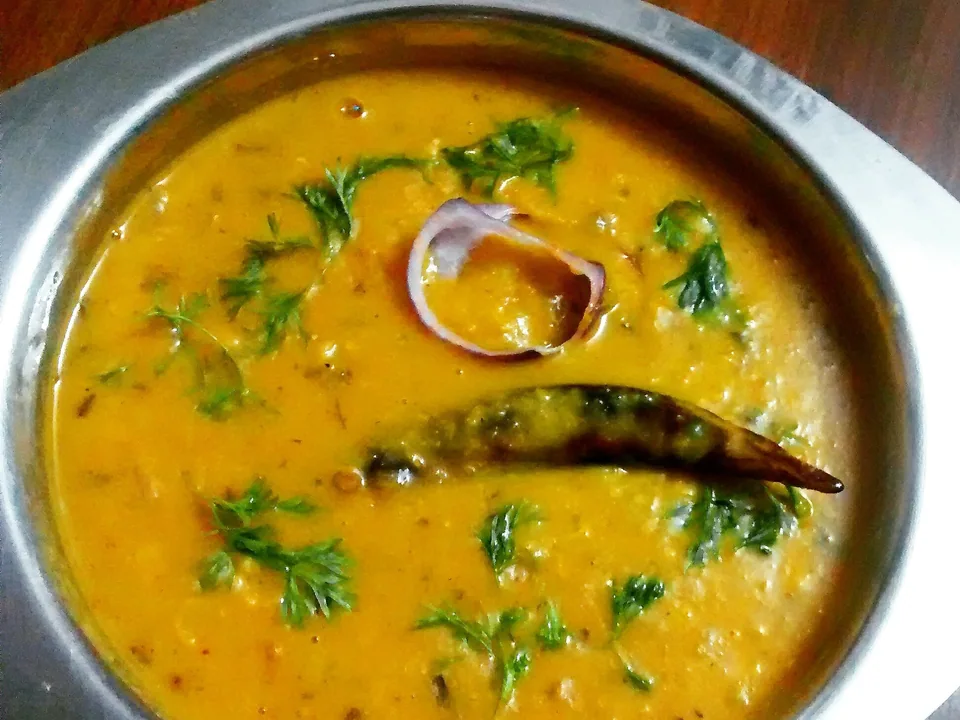 Creamy yellow dal tadka topped with red chile ghee, cumin, browned garlic, dried chiles, and cilantro