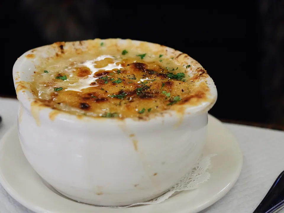 Onion soup in a white crock with a browned melted-cheese crust and parsley