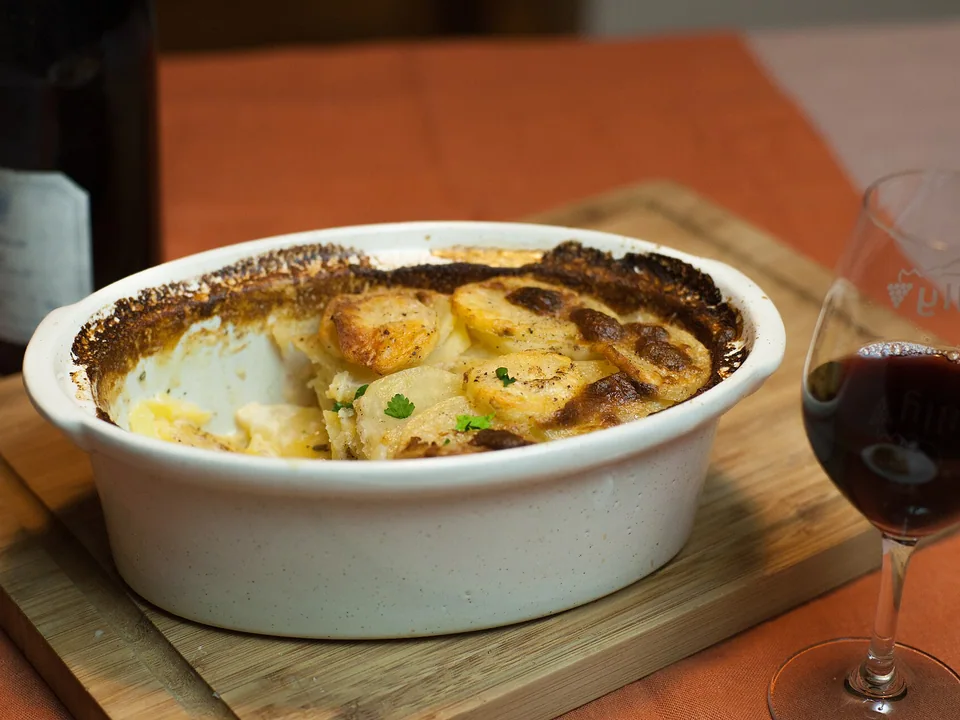 Golden baked potato slices in a white oval gratin dish with a creamy centre
