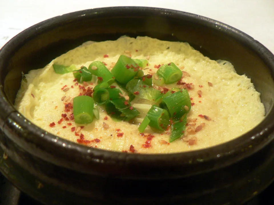 Puffed Korean steamed egg in a hot earthenware pot with scallions and sesame