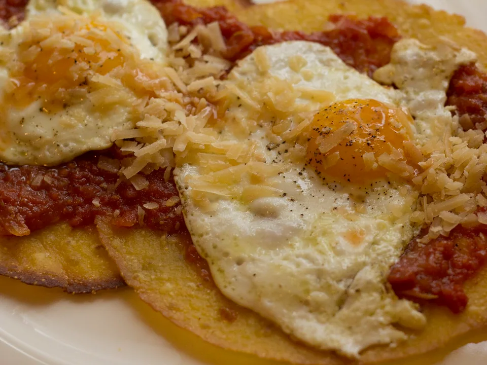 Huevos rancheros with red salsa on corn tortillas and refried beans