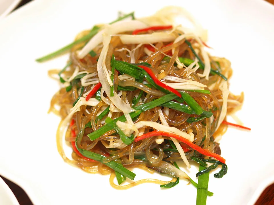 Glossy sweet-potato noodles with garlic chives, carrot, red pepper, onion, and enoki