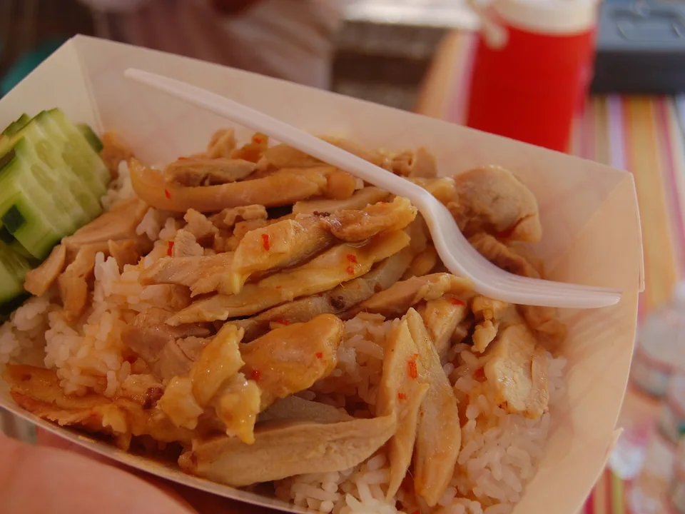 Thai Khao Man Gai with sliced poached chicken, chicken-fat rice, cucumber, soybean chile sauce, and clear broth