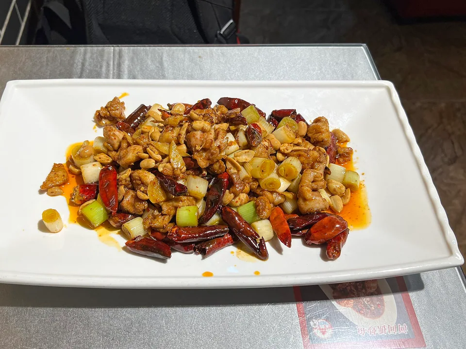 Kung Pao chicken with chicken pieces, dried red chiles, peanuts, and scallions in a glossy brown sauce