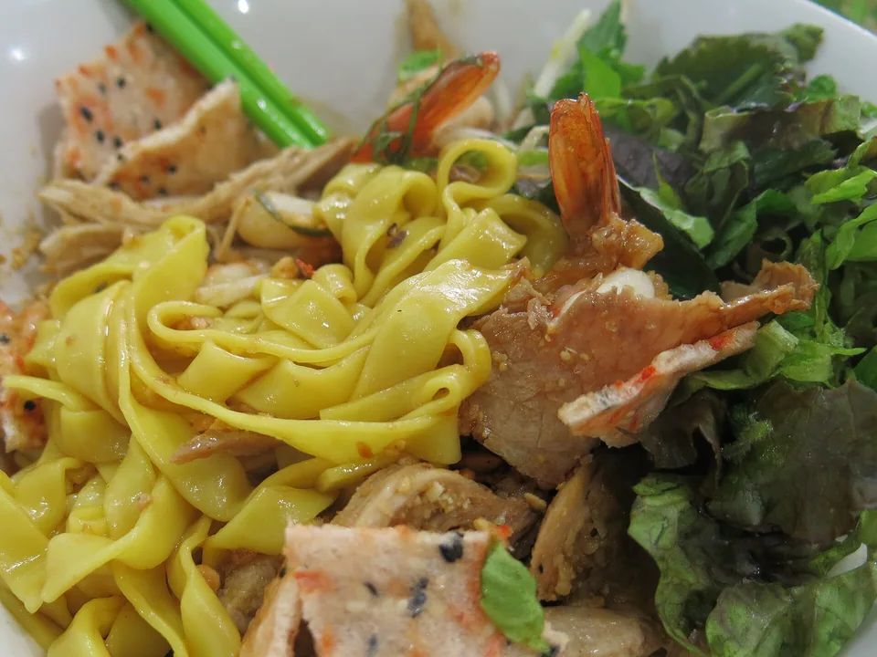 Yellow mì Quảng noodles with pork, shrimp, quail eggs, peanuts, herbs, and sesame crackers