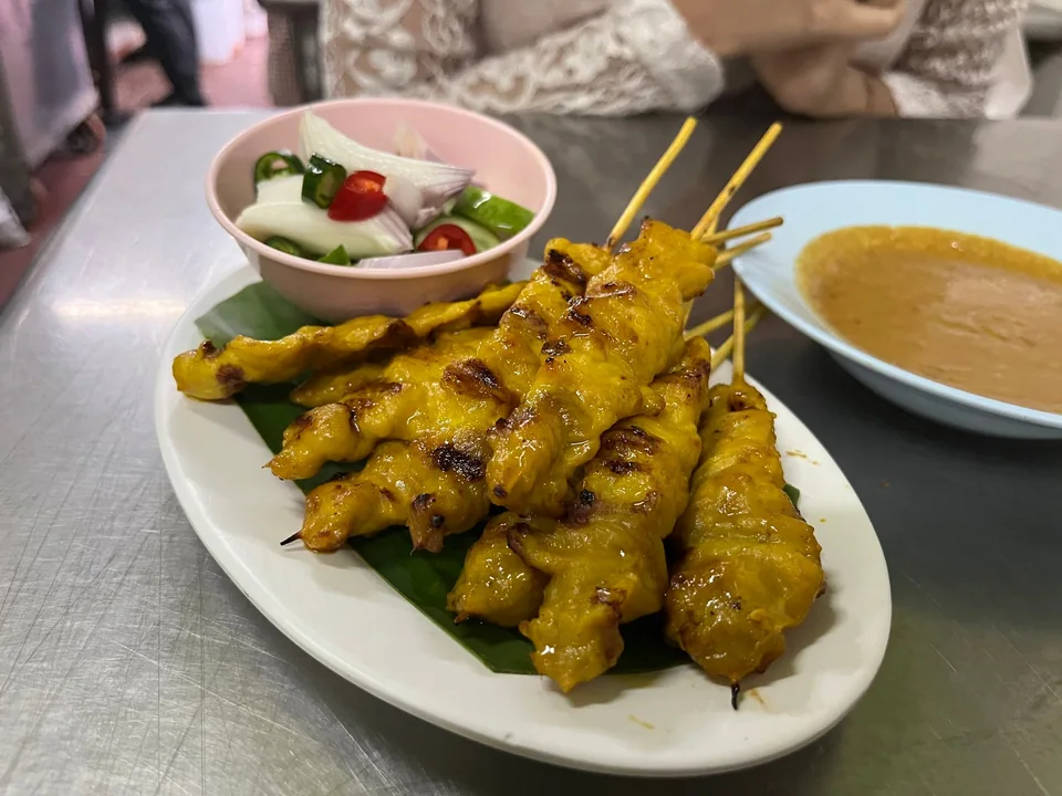 Thai pork satay skewers with golden turmeric marinade, peanut curry sauce, and cucumber relish