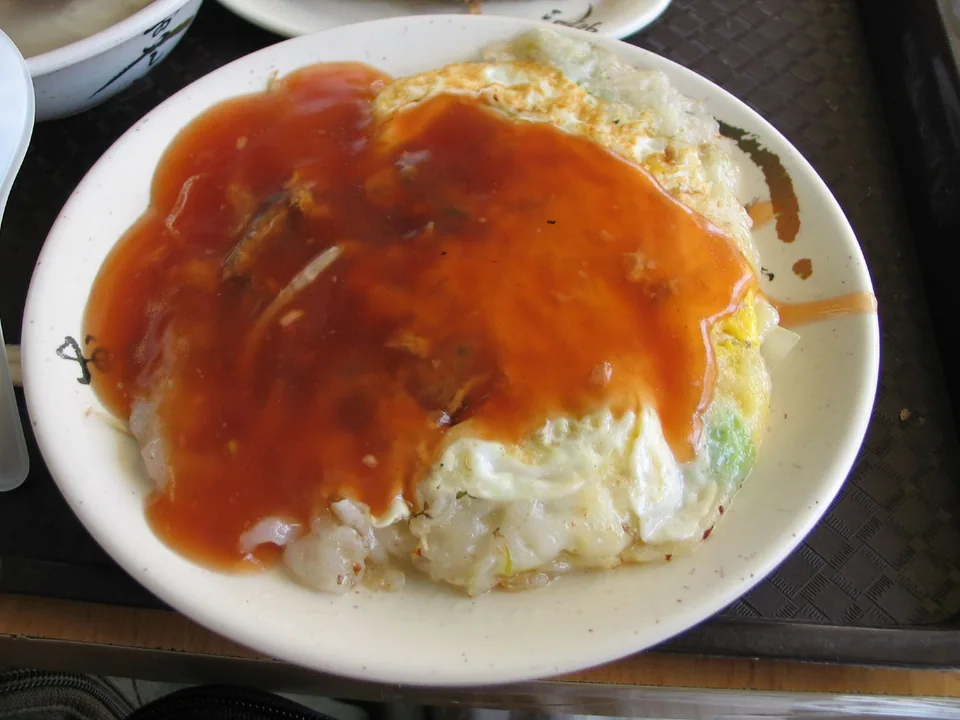 Taiwanese oyster omelette with translucent starch, egg, greens, and glossy red sauce