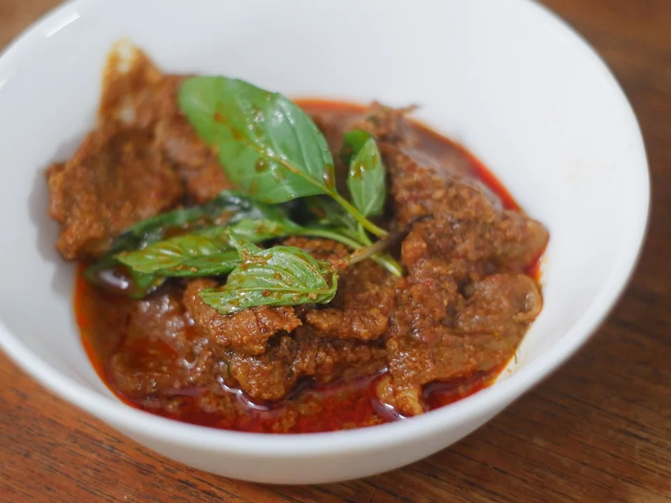 Thick beef Panang curry with coconut, ground peanuts, makrut lime leaf, Thai basil, and red chile
