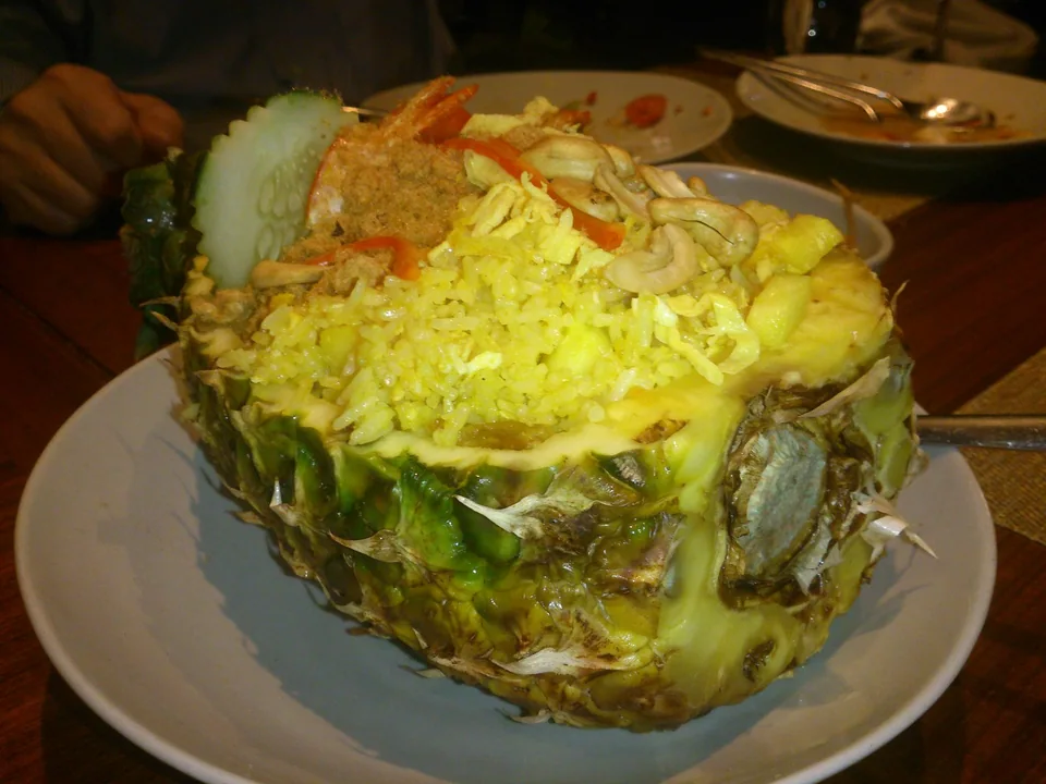 Thai pineapple fried rice with shrimp, egg, curry, cashews, raisins, scallions, and lime in a pineapple shell
