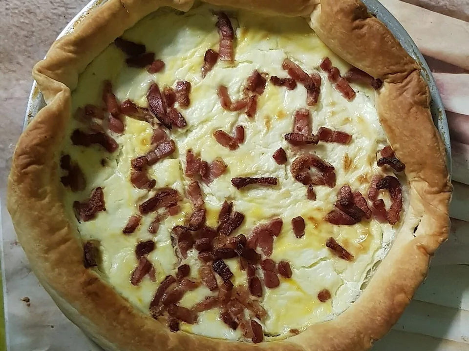 Homemade quiche with golden pastry, pale egg custard and browned bacon strips
