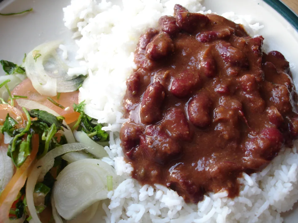 Rajma masala with tender red kidney beans in thick reddish-brown gravy beside basmati rice