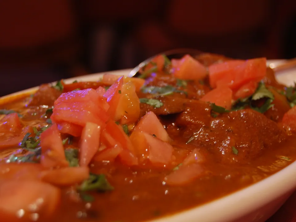 Kashmiri lamb rogan josh with tender bone-in lamb in deep red glossy yogurt-spice gravy