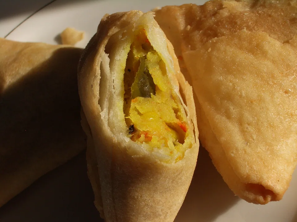 Deep-golden Punjabi samosas with flaky triangular shells and visible dry potato-pea filling