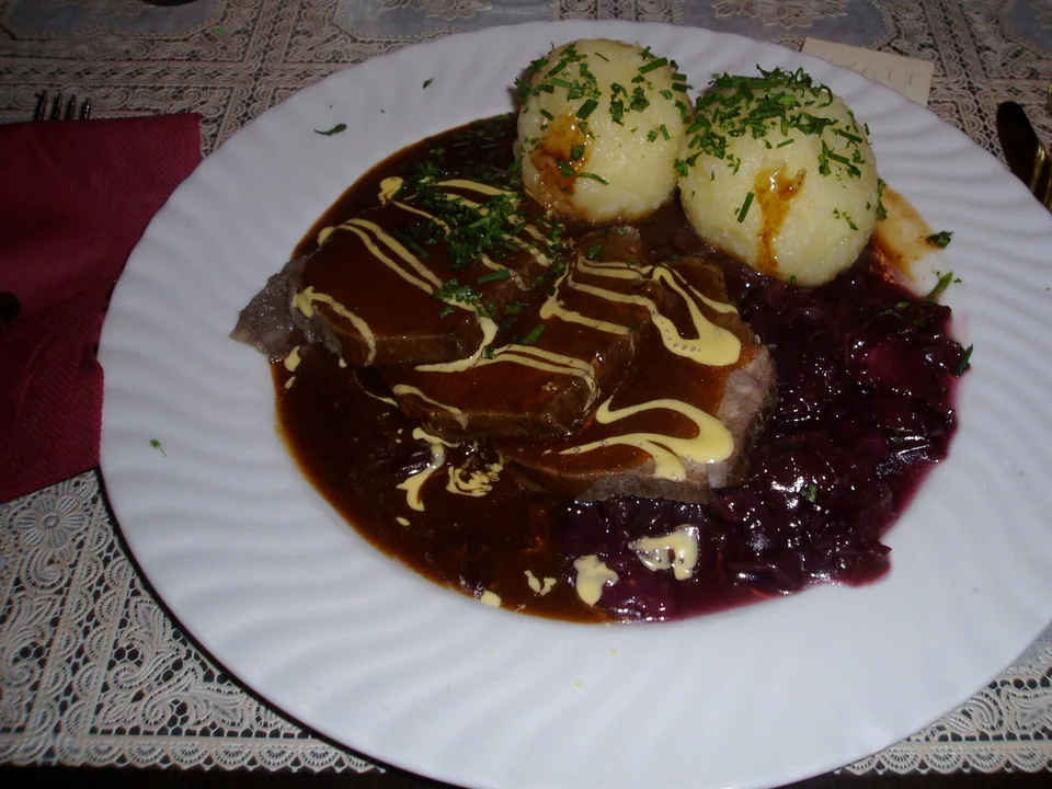 Rhineland Sauerbraten slices with dark gravy, raisins and potato dumplings
