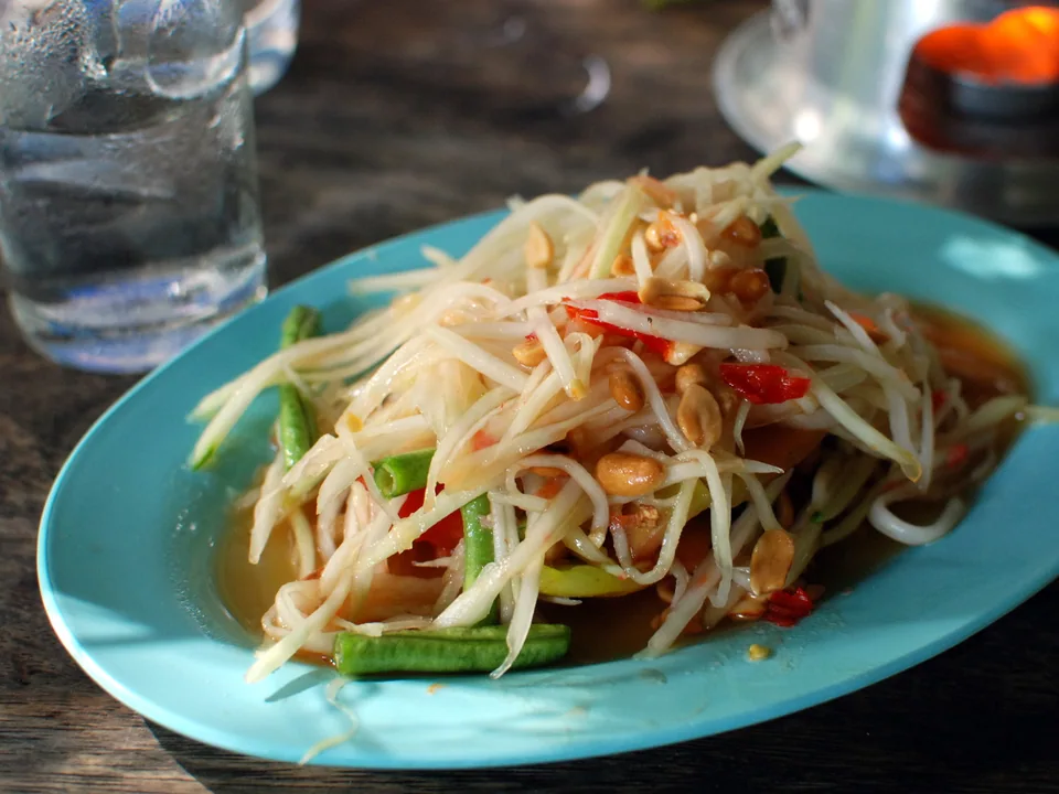 Som Tam Thai with green papaya, tomatoes, long beans, dried shrimp, peanuts, lime, and chile