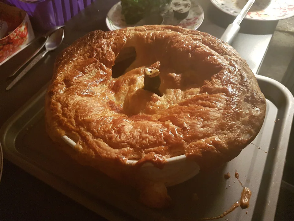 Deep-golden steak and kidney pie with puff pastry lid and dark gravy filling