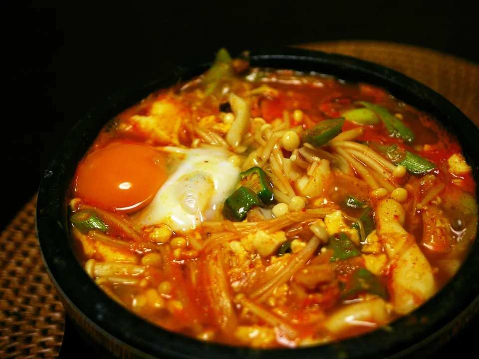 Bubbling red soft-tofu stew with kimchi, pork, enoki, soft-yolk egg, and scallions