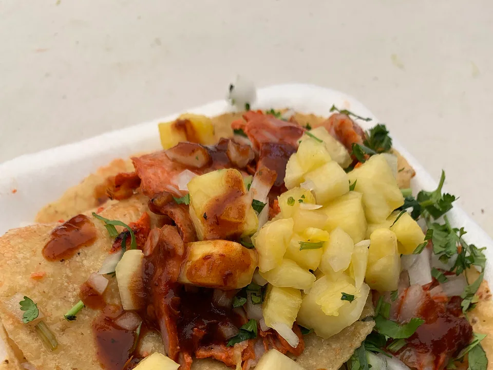 Tacos al pastor with charred pork, pineapple, onion and cilantro