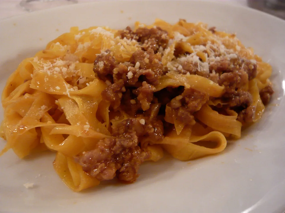 Wide tagliatelle ribbons coated in Bolognese ragù with Parmigiano