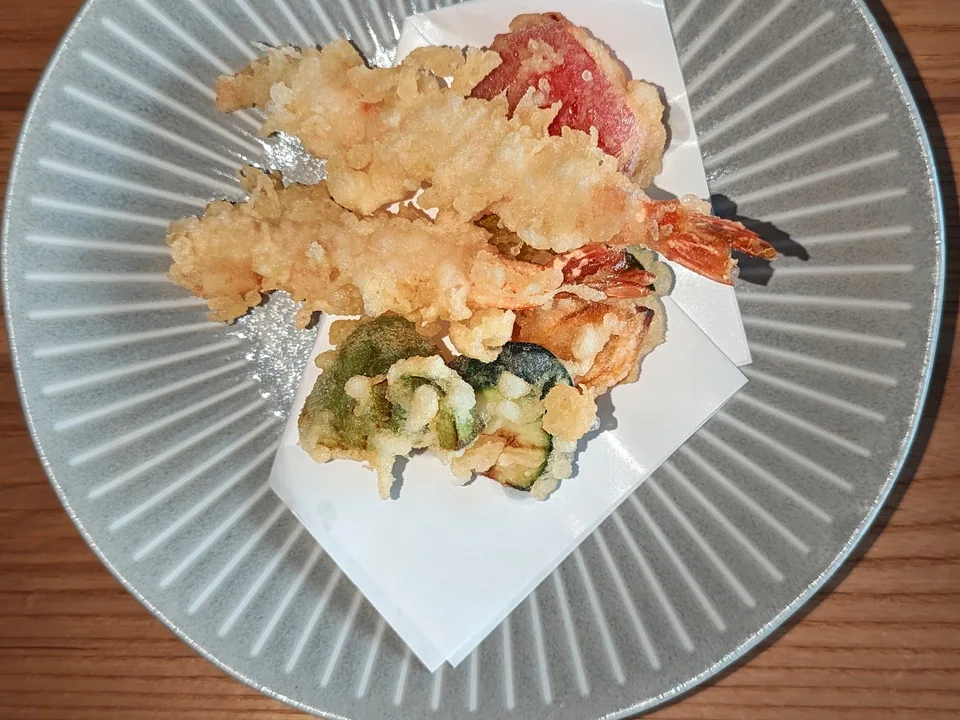 Two shrimp and assorted vegetable tempura on a large gray plate