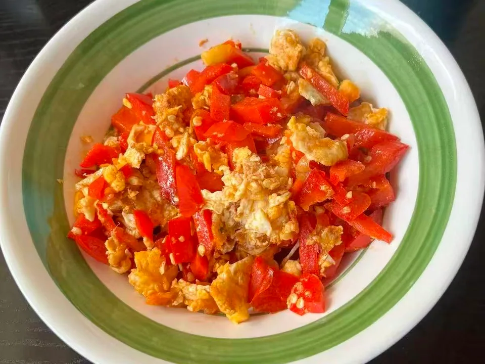 Tomato and egg stir-fry with soft yellow curds, juicy tomato wedges, and sliced scallions in a shallow bowl