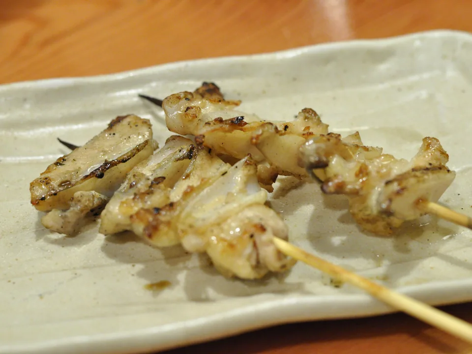 Lightly salted grilled chicken yakitori skewers on a pale ceramic plate